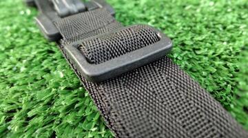 Closeup of black car seat belt on green artificial grass background. photo