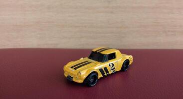 Miniature yellow car toy on red background with copy space for text photo