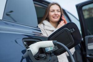 joven negocio mujer repostaje su eléctrico coche a un ev cargando estación. concepto de ambientalmente simpático vehículo. eléctrico coche concepto. verde de viaje. foto