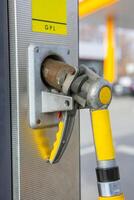 joven mujer participación un combustible boquilla en su mano mientras repostaje coche a gas estación. un detener para repostaje a el gas estación. alimentando el coche con gas. foto