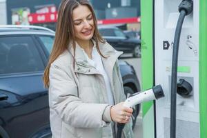 joven negocio mujer repostaje su eléctrico coche a un ev cargando estación. concepto de ambientalmente simpático vehículo. eléctrico coche concepto. verde de viaje. foto