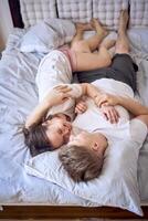 a young couple is lying on the bed, the girl is on the boy's shoulder, tender hugs photo