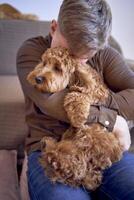 owner hugs the cockapoo girl tightly photo