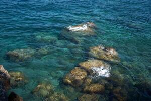 piedras ese son lavado por el limpio, transparente azul agua de el Mediterráneo mar foto