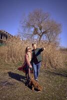 a young stylish couple walking with their cockapoo dog near the river, an unfinished parking lot in the background photo