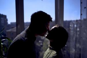 beautiful young couple kissing in the backlight against the window photo
