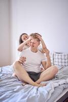 young couple on the bed, the woman combs the man's hair photo