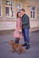 a young couple in love walking through the spring city with a cockapoo photo