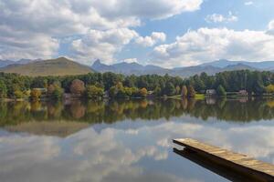 Reflection of clouds and autumn colored trees on the lake photo