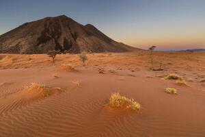 Red sand dune and black rock mountain photo