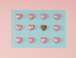 Creative romantic arrangement made with foil wrapped pink chocolate hearts on light pastel pink and blue background. Minimal love concept. Trendy chocolate hearts idea. Chocolate aesthetic. Flat lay. photo