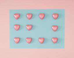 Creative romantic arrangement made with foil wrapped pink chocolate hearts on light pastel pink and blue background. Minimal love concept. Trendy chocolate hearts idea. Chocolate aesthetic. Flat lay. photo