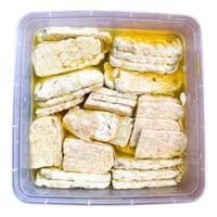Top View Marinate raw tempeh with salt and garlic in a plastic container. isolated on white background photo