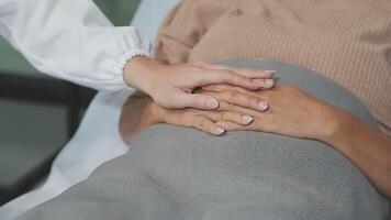 emocional conforto armazenado dentro impressões digitais. tiro do a irreconhecível médico segurando mãos com dela paciente durante uma consulta. video