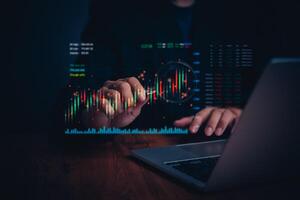 Businessperson using a laptop to study financial graphs and stock market Indicators trading data for candlestick chart investment analysis. photo