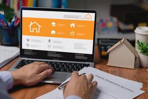 un hombre es utilizando un computadora buscar información comprando y de venta real inmuebles o alquiler un hogar, consiguiendo hogar seguro. Internet en línea tecnología. foto