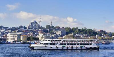 turista barco navegando en el dorado cuerno en frente de el suleymaniye mezquita, Estanbul, Turquía foto