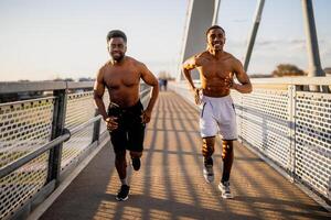 Two african-american friends are jogging on the bridge in the city. photo