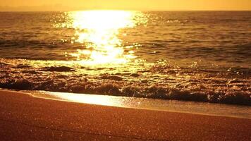 Blurred golden sea at sunset. The sun reflects and sparkles on the waves with bokeh, illuminating the golden sea. Holiday recreation concept. Abstract nautical summer ocean sunset nature background. video