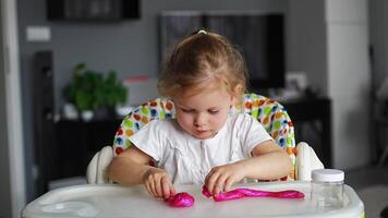 pequeno menina é jogando com uma caseiro Rosa lodo. crianças mãos jogando lodo brinquedo dentro lar. Alto qualidade 4k cenas video