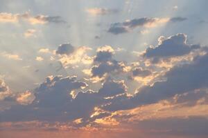 Beautiful sunrise with warm orange sunlight and beams through blue sky photo