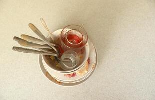 Stack of dirty dishes with food leftovers on the table after meal. Banquet ending concept. Unwashed dishes photo