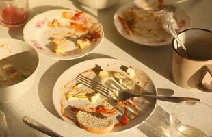 Empty dirty plates with spoons and forks on the table after meal. Banquet ending concept. Unwashed dishes photo