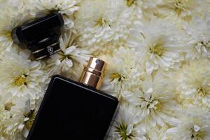 Women fragrance perfume bottle with flowers background close up. Unnamed blank sprayer bottle of perfume photo