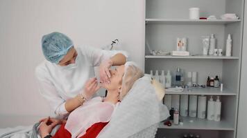 mesoterapia do uma mulher face dentro uma beleza salão. a cosmetologista faz injeções para dentro a pacientes face. a procedimento do lábio aumento, redução do rugas em a face, pele rejuvenescimento video