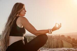 aptitud mujer. contento de edad mediana aptitud mujer haciendo extensión y pilates en un rock cerca bosque a puesta de sol. hembra aptitud yoga rutina. sano estilo de vida con atención en bienestar y relajación. foto