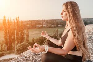 aptitud mujer. contento de edad mediana aptitud mujer haciendo extensión y pilates en un rock cerca bosque a puesta de sol. hembra aptitud yoga rutina. sano estilo de vida con atención en bienestar y relajación. foto