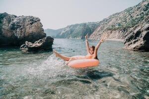 Woman summer sea. Happy woman swimming with inflatable donut on the beach in summer sunny day, surrounded by volcanic mountains. Summer vacation concept. photo