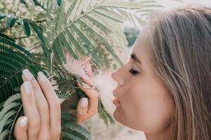 Beauty portrait of happy woman closeup. Young girl smelling Chinese acacia pink blossoming flowers. Portrait of young woman in blooming spring, summer garden. Romantic vibe. Female and nature photo