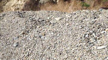 Man wearing boots jumps from a pebble beach slide. Slow motion video