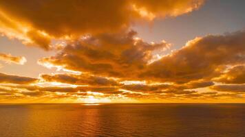 Timelapse Dramatic sunset with fluffy clouds moving in golden burning sky over sea. Abstract aerial nature summer ocean sunset sea and sky background. Vacation, travel and holiday concept. Aerial view video