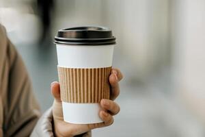 ai generado mano persona sostener caliente bebida desechable blanco papel café taza mangas en aislado antecedentes. generativo ai. foto