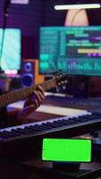 Vertical Video Songwriter playing acoustic guitar in home studio with greenscreen display running on smartphone app. Musician practices singing on musical instrument with strings, isolated screen. Camera B.