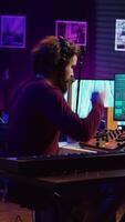 verticale vidéo l'audio technicien mélange et Maîtriser Chansons sur choucas logiciel, création amusement atmosphère avec acoustique et amplificateur. du son designer enregistrement airs sur dj panneau planche dans le sien Accueil studio. caméra b. video