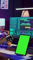vertikal video audio ingenjör praxis inställning hans akustisk gitarr i Hem studio, tittar på en video handledning uppkopplad via läsplatta med grönskärm. musiker inlärning till spela instrument och skapa musik. kamera b.