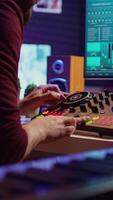 Vertical Video Sound engineer mixing and mastering sounds with electronic audio console, pressing controls and pre amp knobs. Music producer improving sound quality, synchronize soundtracks. Camera B.