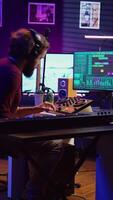 verticaal video blij artiest spelen piano toetsenbord en opname deuntjes voor menging en beheersen sessie, genieten van midi controleur prestatie in huis studio. energiek muziek- producent creëren soundtracks. camera b.