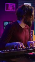 verticaal video muziek- producent spelen zijn lied Aan piano toetsenbord en het zingen Bij microfoon, opname soundtrack naar Bewerk Aan menging troosten. componist werken met synthesizer in huis studio. camera b.