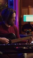 verticale vidéo musicien pièces acoustique guitare et enregistrements mélodie à composer Nouveau chanson et airs. ordinateur écran montrant choucas Logiciel interface avec des bandes sonores, du son ingénieur dans la musique production. caméra un. video