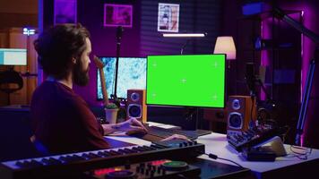 Music producer learning to use mixing console and soundboard, using online tutorial lesson on greenscreen. Artist learns to edit songs and add audio effects, mixing and mastering tracks. Camera B. video