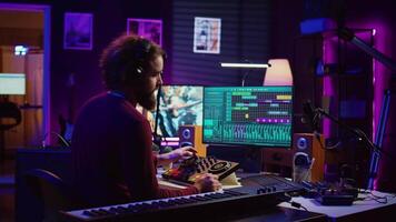 Musician recording electronic piano tunes and having fun in his home studio, editing and mixing recorded tracks to enhance the sound and achieve high quality audio. Producing lively songs. Camera B. video