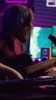 vertical vídeo creativo compositor de canciones canto un canción en micrófono y jugando su guitarra, acústico Ingenieria tecnología con grajilla software en ordenador personal. artista creando música con instrumento y mezcla consola. cámara una. video