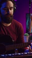 Vertical Video Musical composer recording his guitar tunes and adding piano key sounds, creating a beautiful song with mixing console and daw software. Sound engineer working with electronic tools. Camera B.