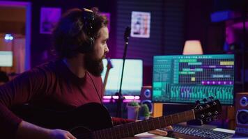 Young artist composing a song on electronic piano keyboard at home recording studio. Audio engineer playing MIDI controller, working on producing a soundtrack, soundboard tools. Camera B. video