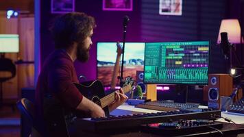 muziek- producent menging gitaar geluiden gespeeld door hem Aan akoestisch instrument, gebruik makend van elektronisch klankbord troosten en daw software. geschoold musicus ontwikkelen nieuw deuntjes, huis studio. camera a. video