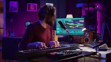 muziek- producent spelen zijn lied Aan piano toetsenbord en het zingen Bij microfoon, opname soundtrack naar Bewerk Aan menging troosten. componist werken met synthesizer in huis studio. camera b. video